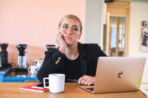 Lady sitting at her desk thinking with her hand on her cheek. Living your best like in your 30's.