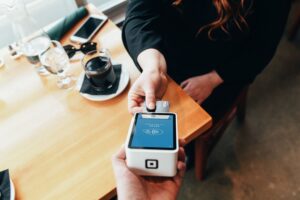 Man using a Square machine to process a transaction. Change your money mindset to achieve your goals.