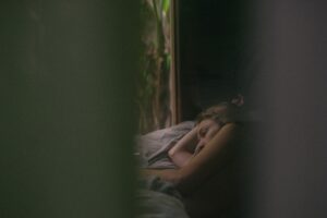 Dark photo of woman sleeping in a cabin in the woods. 